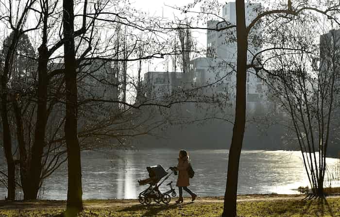 Maman qui se sent seule et épuisée se promenant avec sa poussette dans un parc, illustrant la solitude de la parentalité