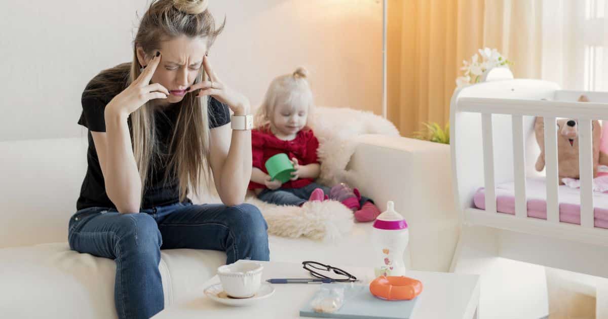Mère assise sur un canapé avec sa fille, l’air préoccupé, illustrant les symptômes du burn-out familial et les questionnements parentaux